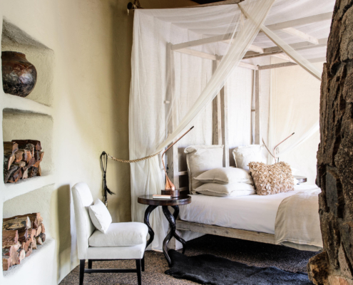 singita_boulders_lodge_river_suite_bedroom_with_white_chair_adriaan_louw
